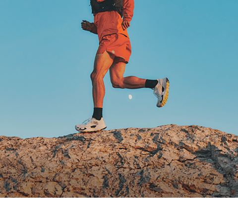 A man runs in rocky terrain in his The North Face sneakers. 