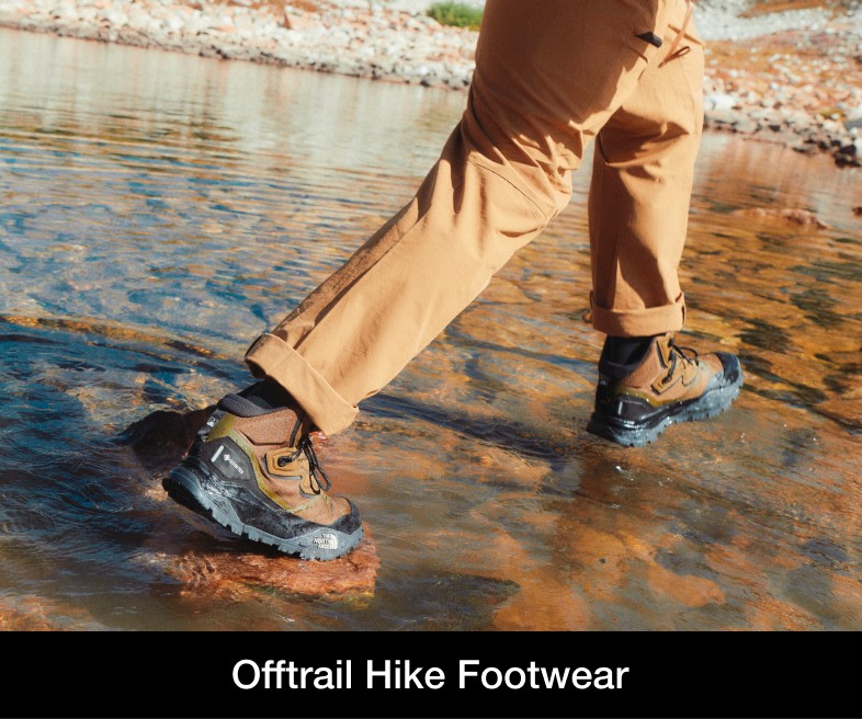 A man wearing low-rise, blue hiking shoes with black socks. He’s scaling red rocks. 