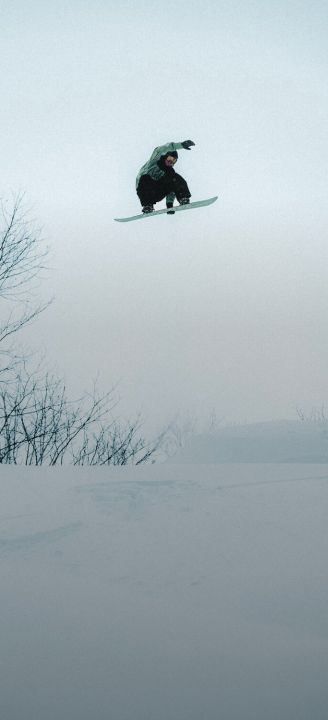 Two people tethered together with a rope walking through snow with an epic peak in the background.