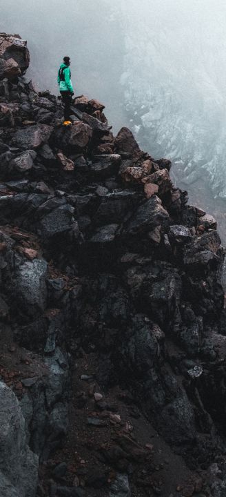 Two people tethered together with a rope walking through snow with an epic peak in the background.