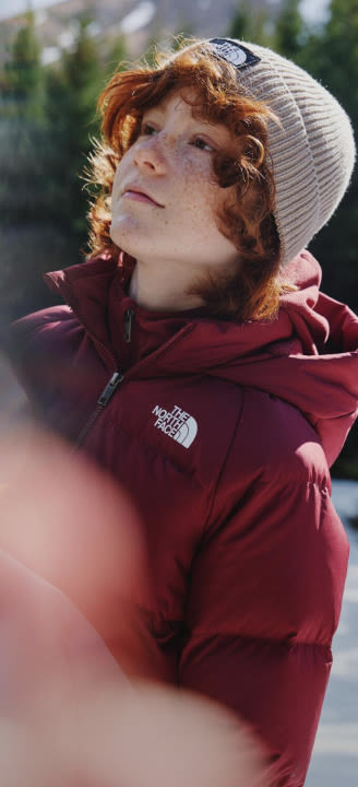 A boy in a red jacket/tan hoodie looking to the left.