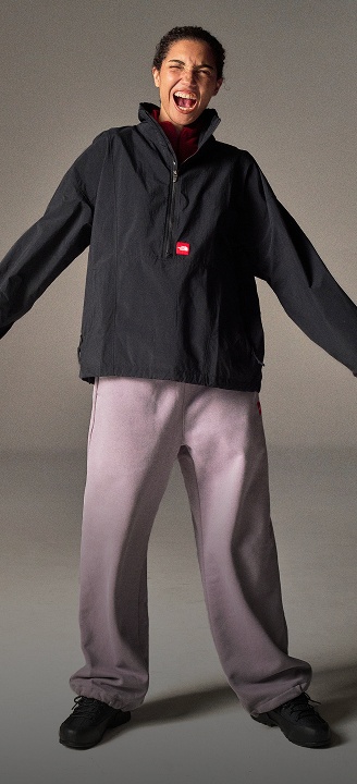 A woman in a black 1/2 zip jacket and purple sweatpants