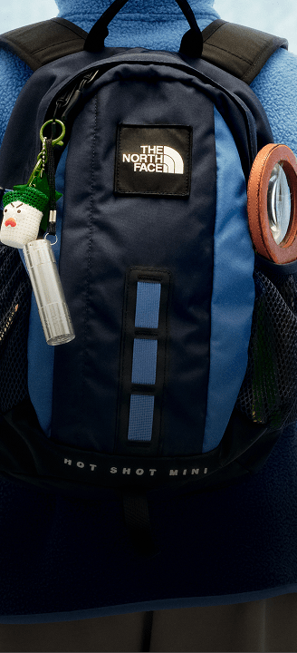 Small child with back to camera wearing a blue and black backpack.