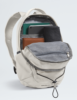 Un sac à dos blanc ouvert montre qu’il peut contenir un ordinateur portatif, un cahier de notes, une tablette et un chandail léger.