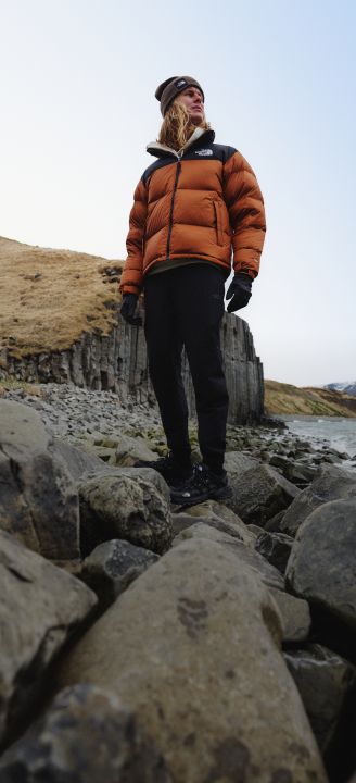 A person standing on a rock wearing a Nuptse jacket.