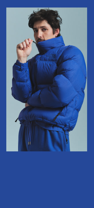 A man in a blue Nuptse all the way zipped, the image has a blue frame around it.