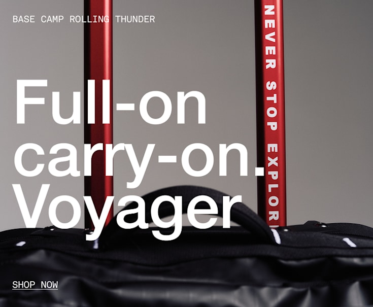 he top of black rolling luggage, you can read “NEVER STOP EXPLORING” on the handle.