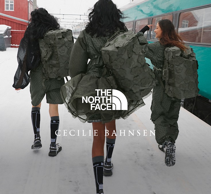 Three models walking through a snowy train station wearing The North Face x Cecilie Bahnsen collection with Anna Base Camp Duffel bags.