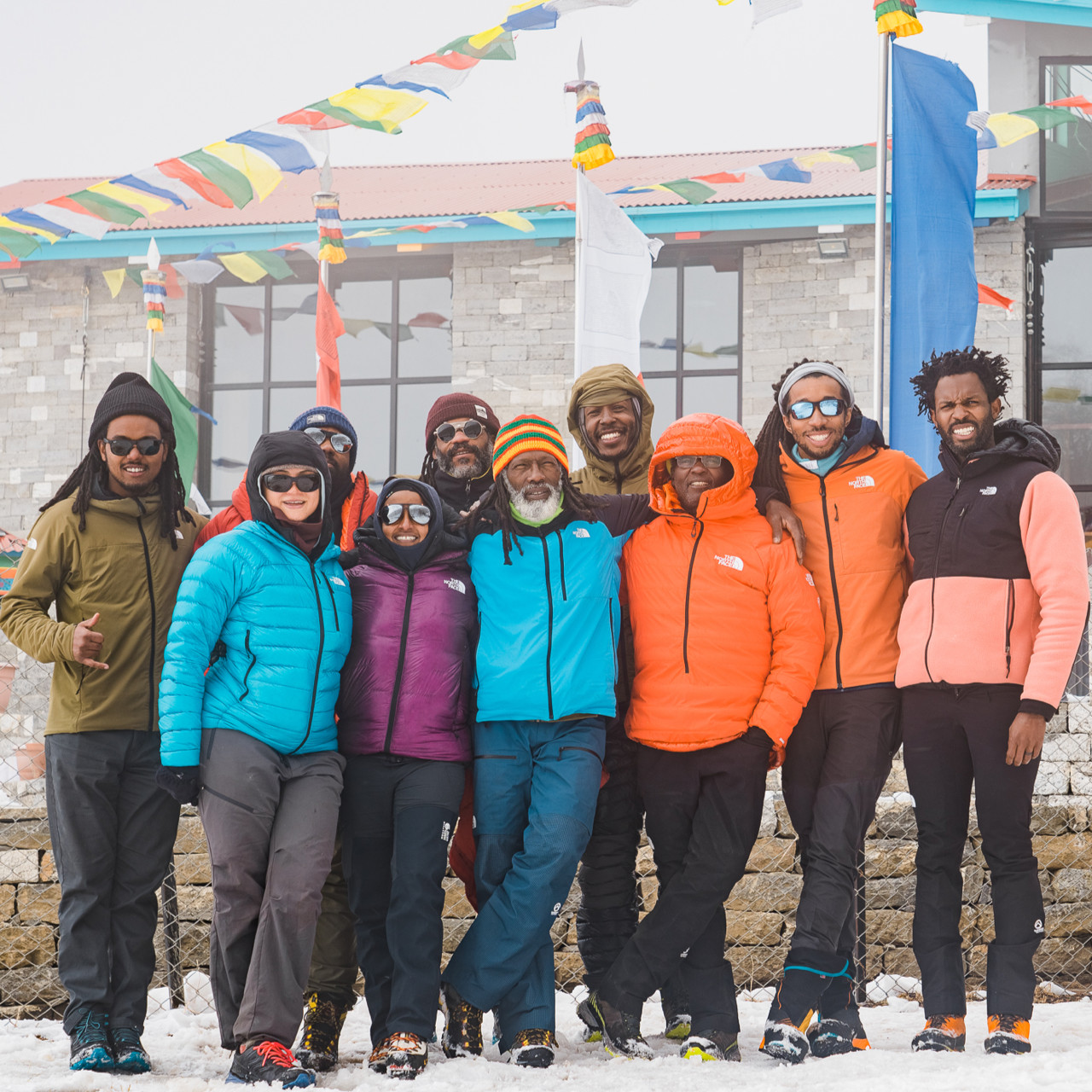 Surrounded by brightly colored prayer flags, the Full Circle Everest team are all smiles during their ascent of Everest.
