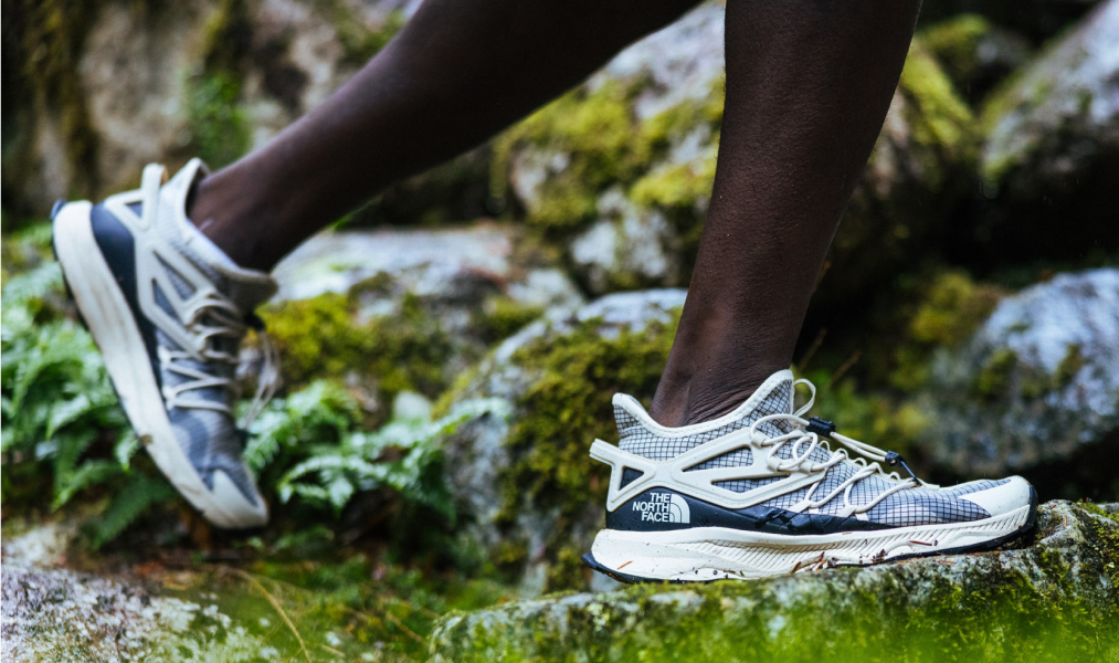 an up close image of the north face hiking boots hiking on mossy green rocks