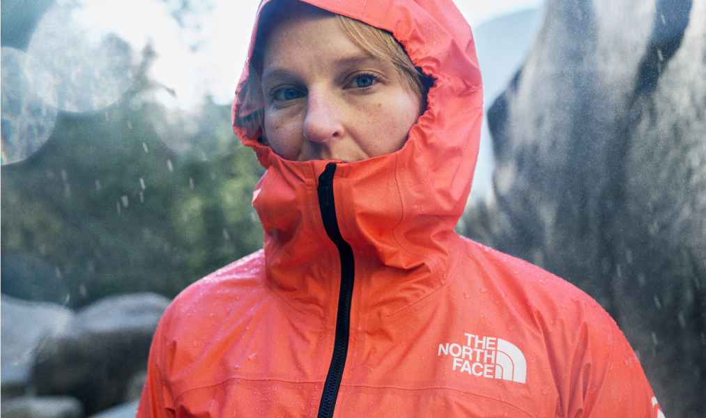 Person standing in the rain wearing a The North Face hooded waterproof jacket.