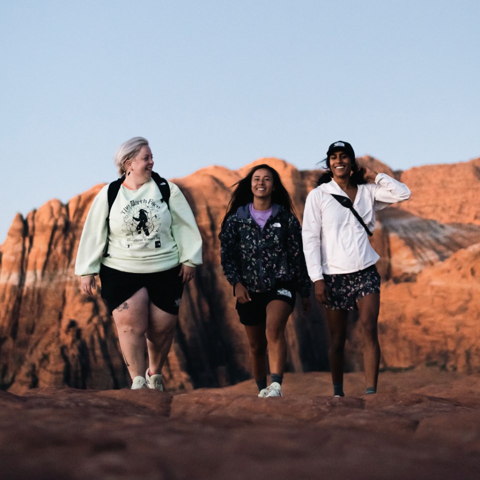 Three people laughing while on a hike at sunset.