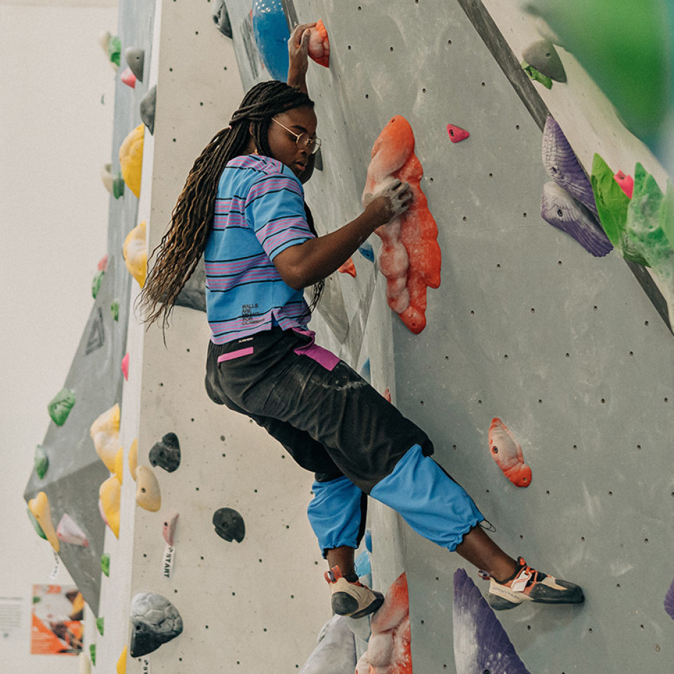 A person focusing on climbing a bouldering wall.