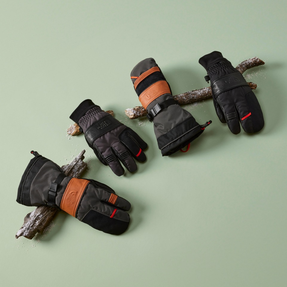 Array or Montana Pro gloves and mittens laying on a green background.