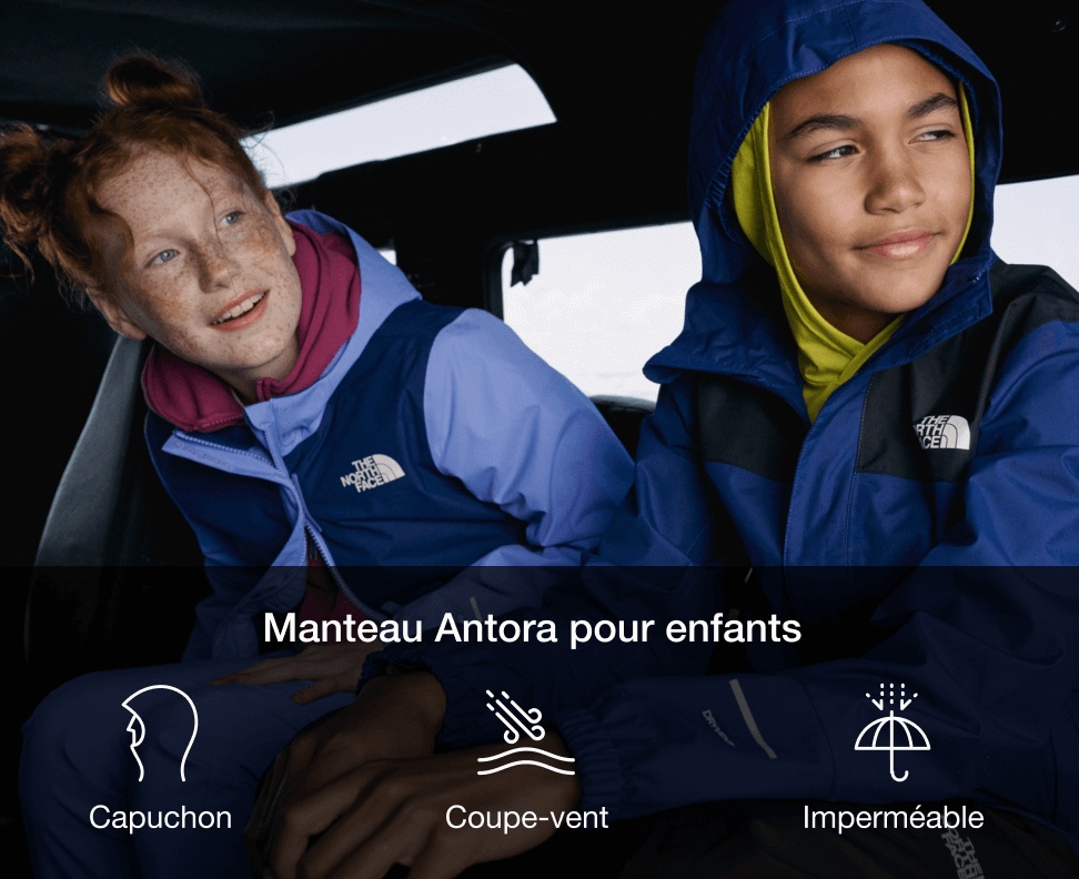 Two kids inside a car. To the left a red-headed girl in a light purple rain jacket. To the right a boy in a two-toned blue rain jacket. 