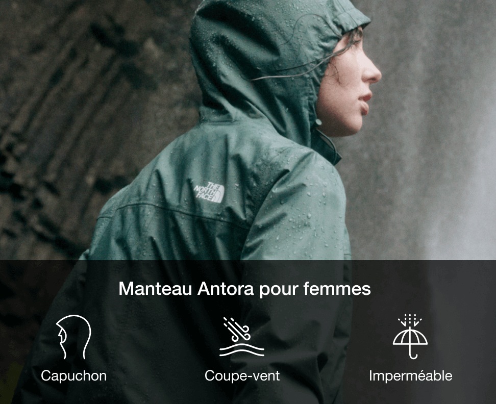 A woman in a green rain jacket with the hood up looking to the left. 