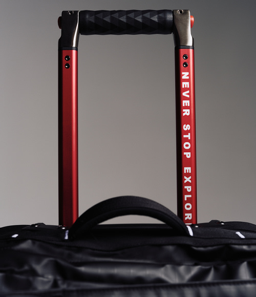 The top of black rolling luggage, you can read “NEVER STOP EXPLORING” on the handle.