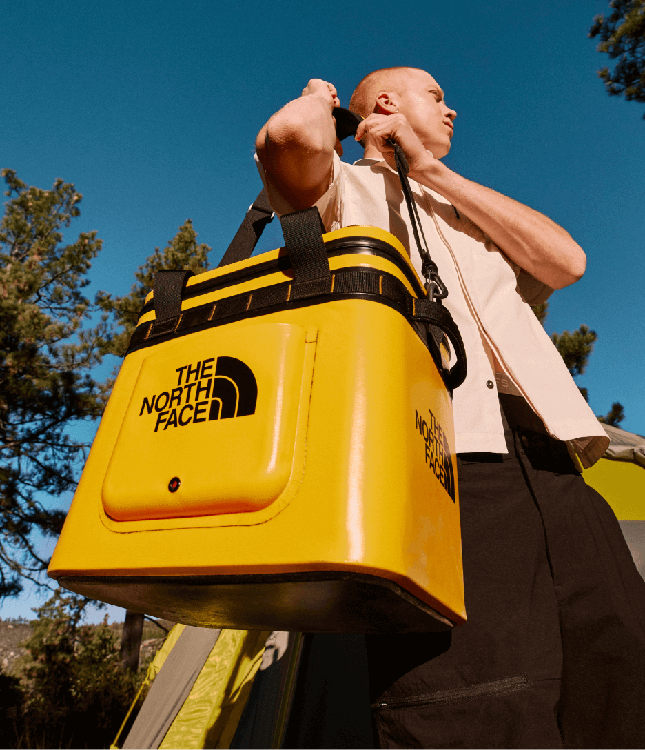 A person holding a yellow cooler from The North Face.