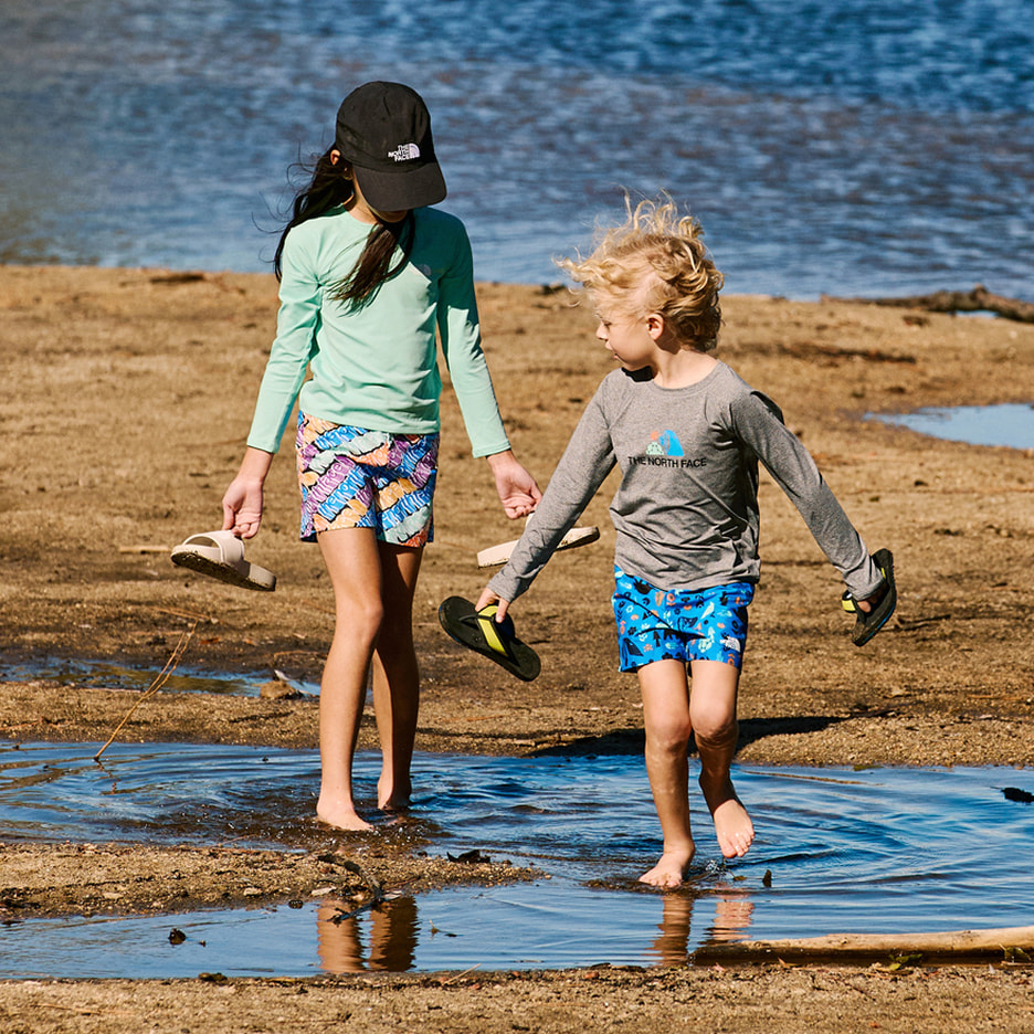 Two young campers carrying a gear box to their campsite.