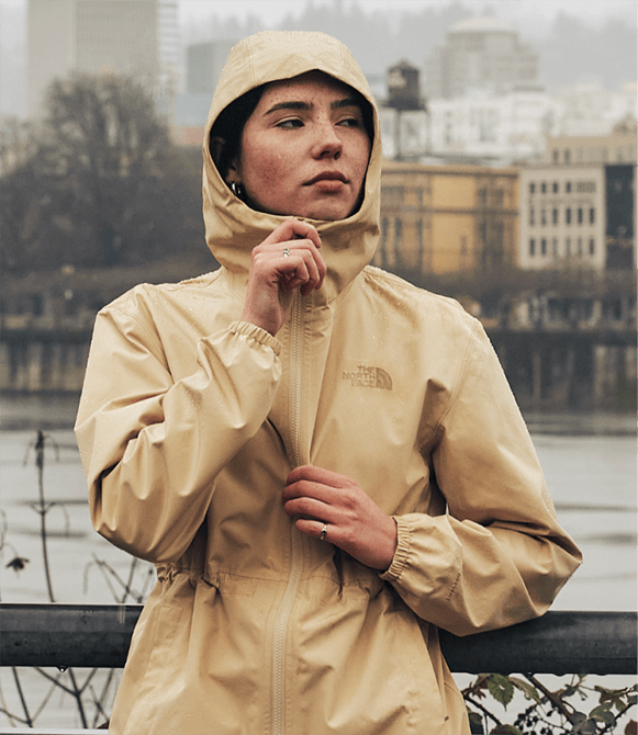 A woman wear a rain jacket from The North Face with the hood up.