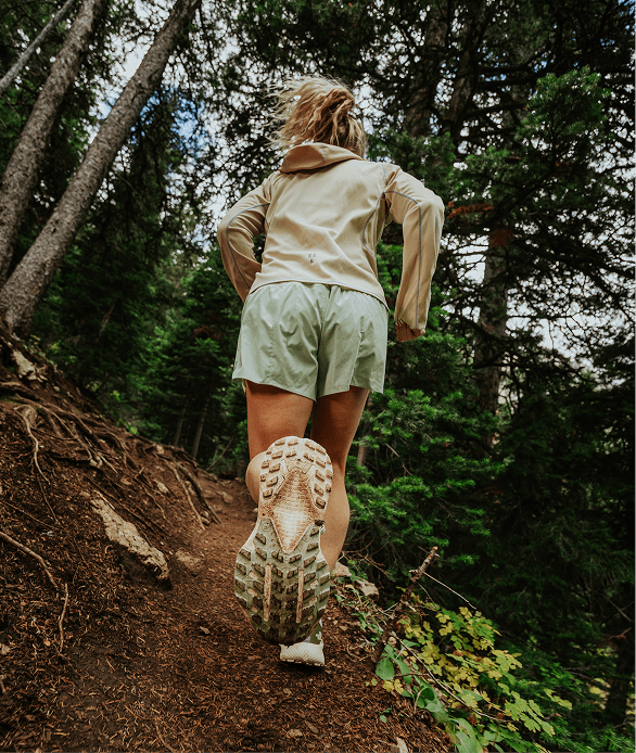 A woman runs up a trail wearing apparel from The North Face.