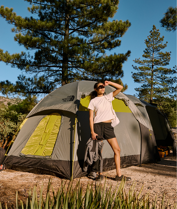 A woman stands in front of a camping tent from The North Face.