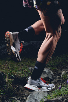 A close up of a person’s legs, they’re wearing black socks and Vectiv shoes and running to the left.
