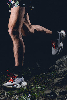 A close up of a person’s legs, they’re wearing black socks and Vectiv shoes and running to the left.