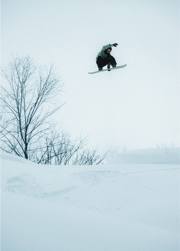A snowboarder catching air and grabbing their board.