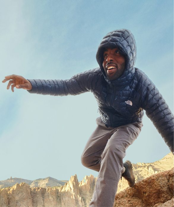 A woman in black pants and white/gray jacket, climbing a ladder.