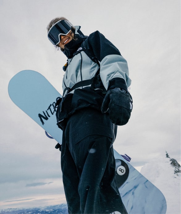 A woman in black socks and tan ankle-height hiking shoes pushing herself up rocks. The shoe is the focal point.