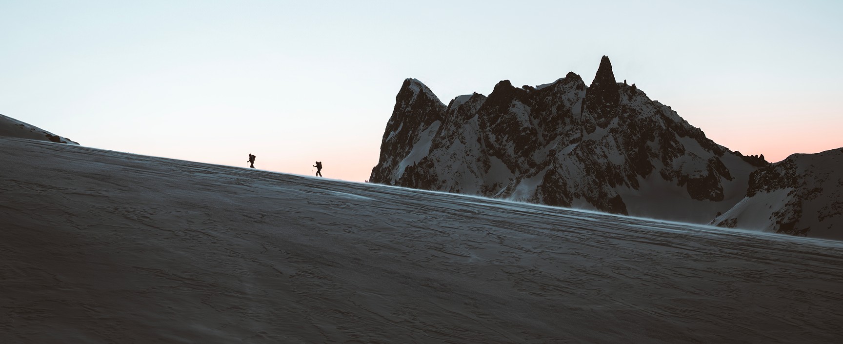 Snowy landscape with two hikers in the background.