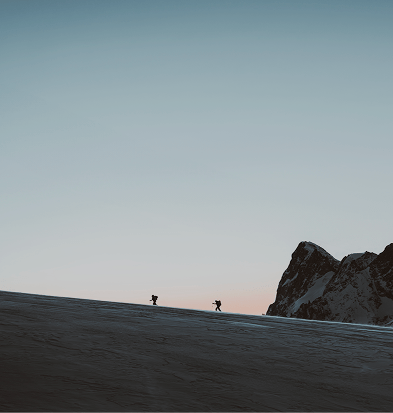 Snowy landscape with two hikers in the background.