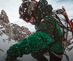 Man in an AMK outfit climbing in the snow.