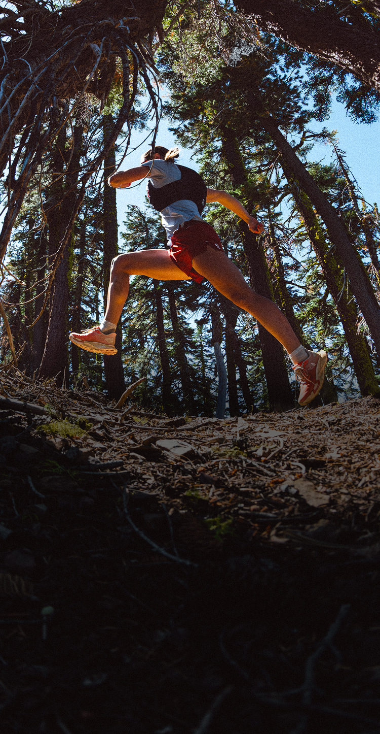 Person wearing Summit Series apparel running through wooded, mountain terrain. 