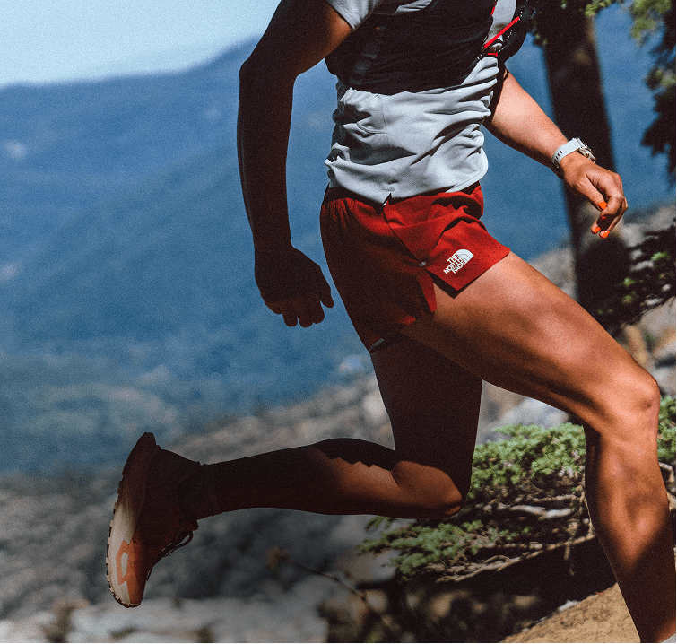 Closeup of red Pacesetter Shorts on runner. Leg is kicked back in mid-stride, The North Face logo is clearly visible.