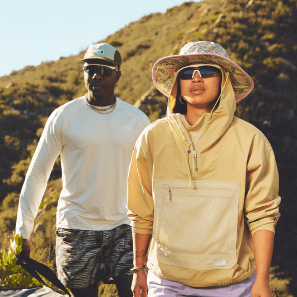 man and woman hiking in hats and sunglasses in a mountainous landscape