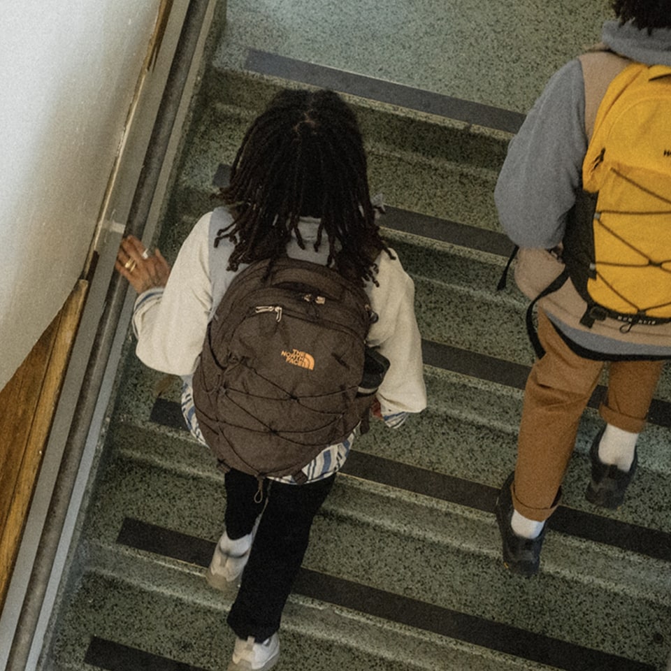 boy and girl walking up a staircase in a school wearing The North Face Borealis Backpacks