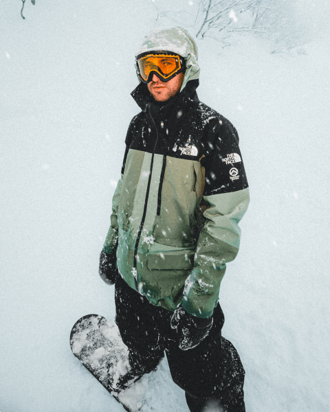 Image of The North Face athlete Nik Baden standing in a snow storm on his snowboard.