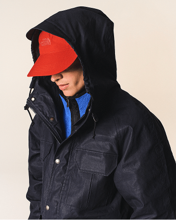  Cream background with man wearing navy parka and red hat with his nose and chin visible and a blue fleece.  
