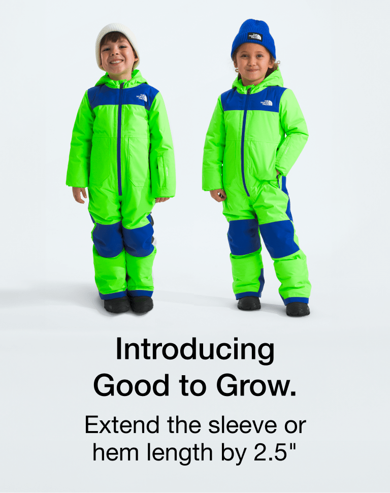 Two kids wearing neon green/blue snowsuits. The kid on the left has a white beanie on and the kid on the left is wearing a blue beanie.