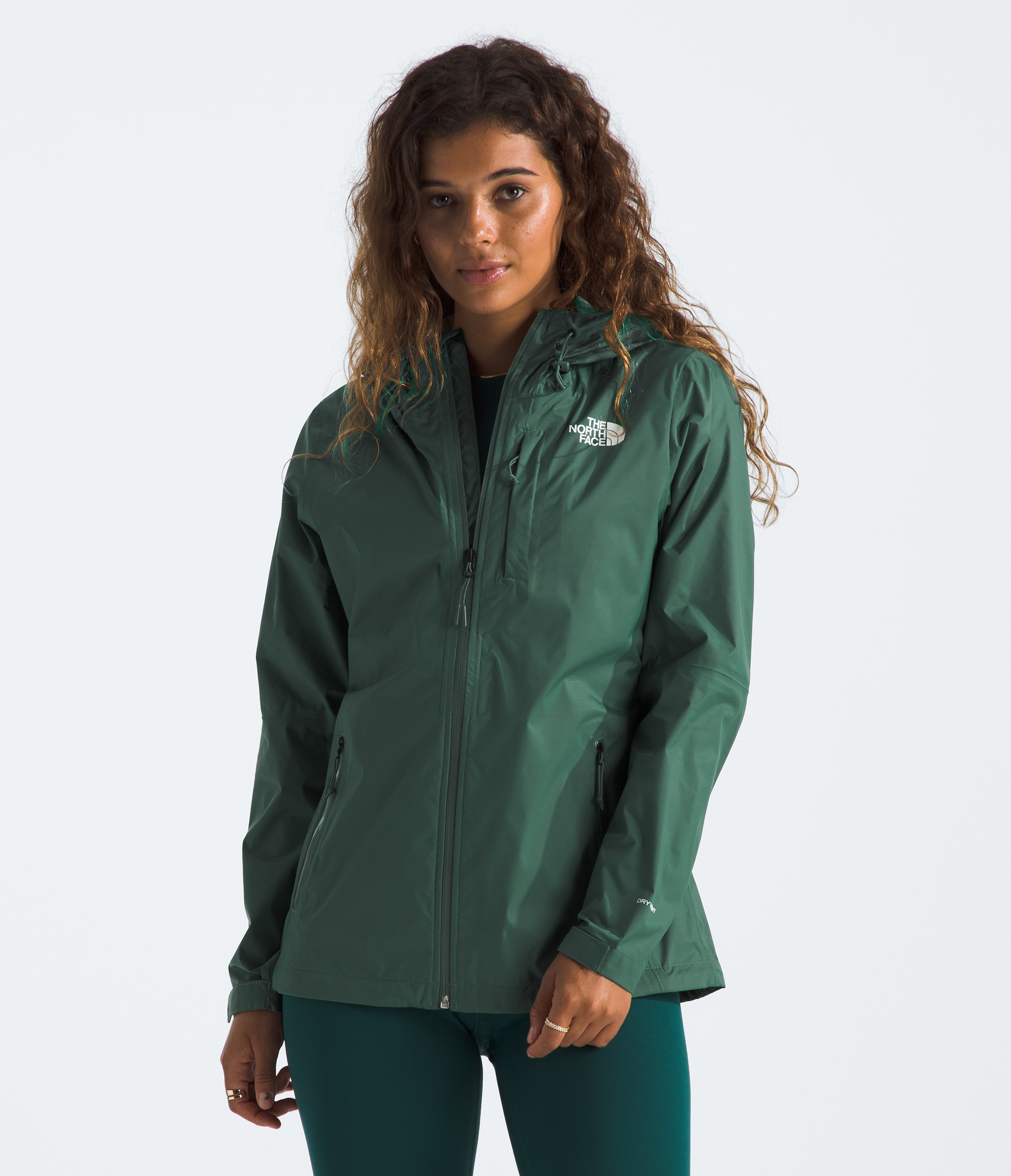 A woman in a green rain jacket with the hood up looking to the left.