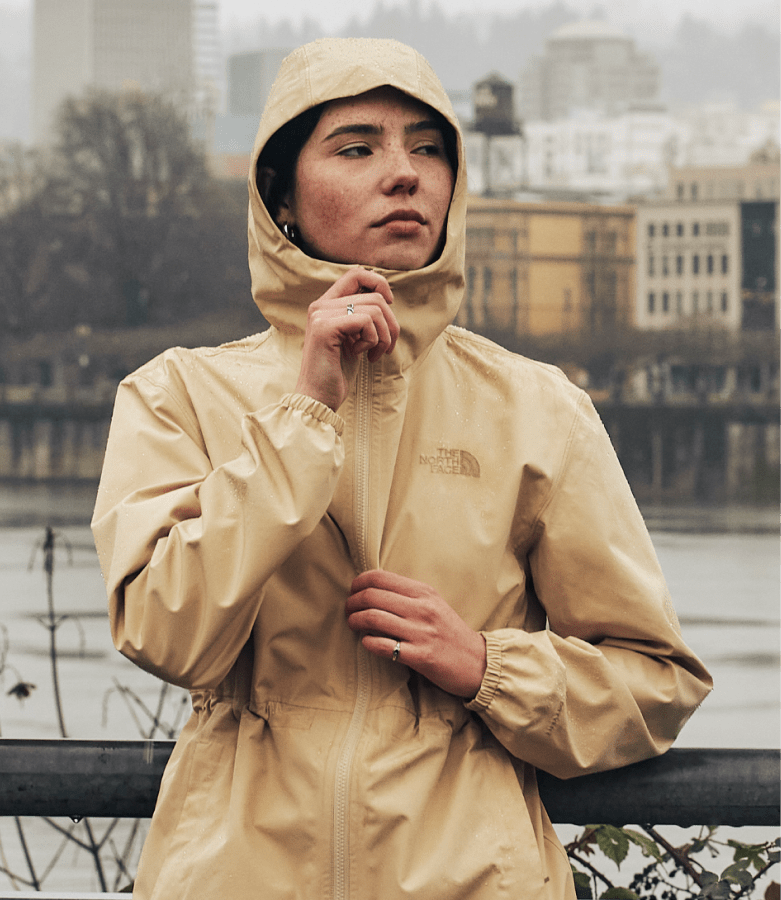 A woman wear a rain jacket from The North Face with the hood up.