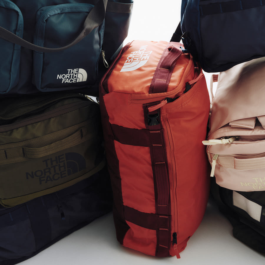 The top part of blue rolling luggage focusing on the red handle. 