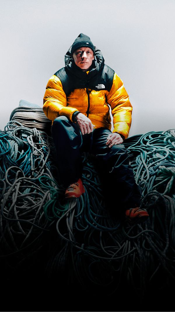 Jim Morrison is wearing a yellow Summit Nuptse jacket sitting on top of a pile of climbing rope.